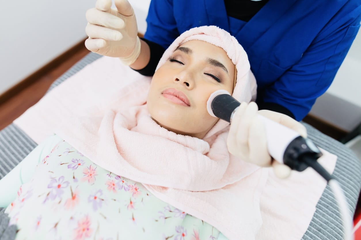 The cosmetologist makes the procedure Microdermabrasion of the facial skin of a beautiful, young woman in a beauty salon